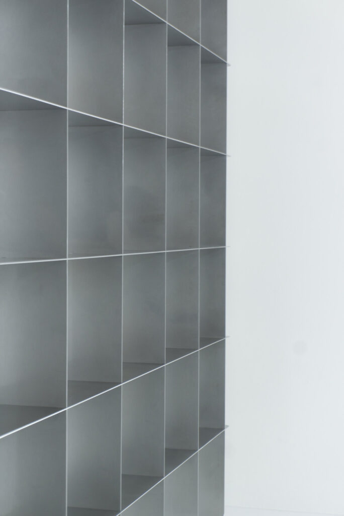 Detail of the straight dividers of a custom Mesh stainless steel bookcase