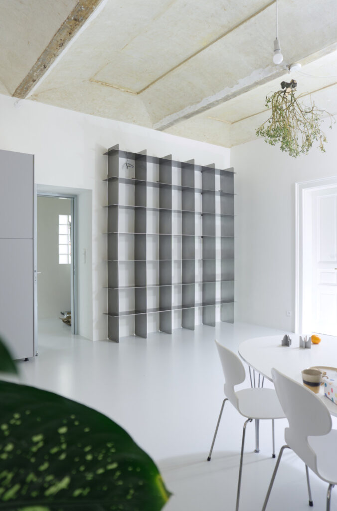 Custom Mesh stainless steel bookcase beside a dining table